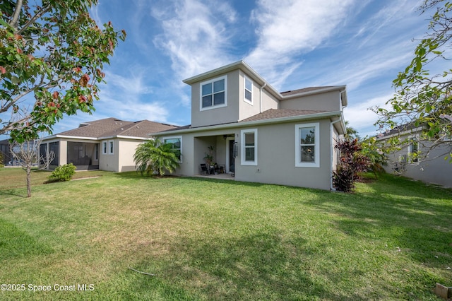 rear view of property featuring a sunroom, stucco siding, a yard, and a patio area
