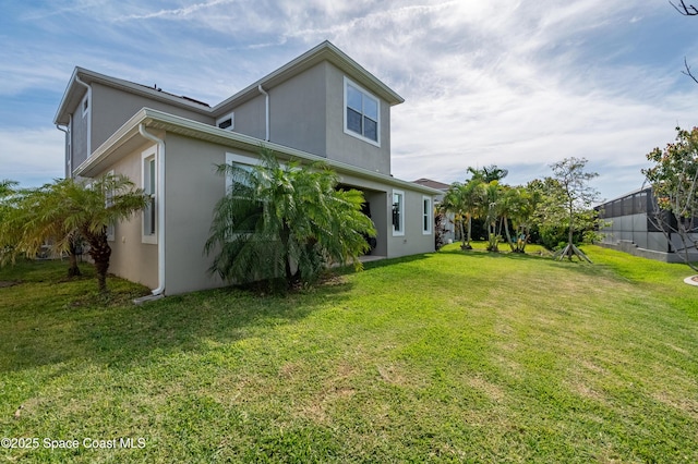 back of property featuring a lawn and stucco siding