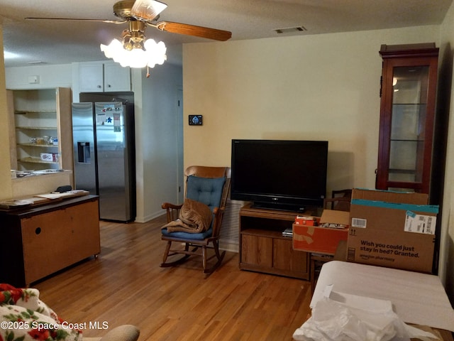 living room featuring ceiling fan, light wood-type flooring, and visible vents