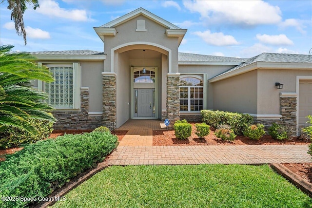 entrance to property featuring a garage, stucco siding, and stone siding