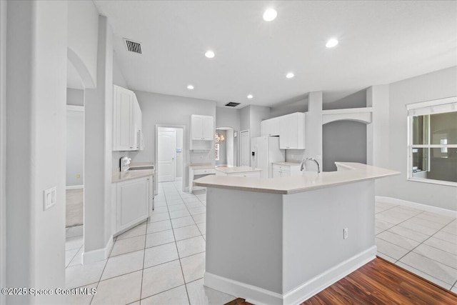 kitchen with visible vents, a large island, light countertops, light tile patterned floors, and white fridge with ice dispenser