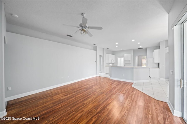 unfurnished living room featuring ceiling fan, visible vents, baseboards, and light wood-style floors