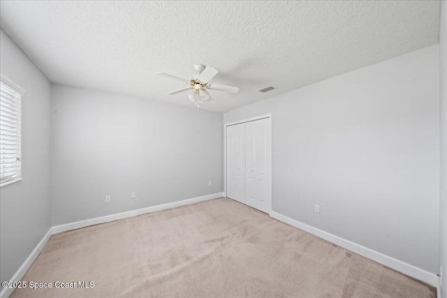 unfurnished bedroom featuring light carpet, a closet, a textured ceiling, and visible vents