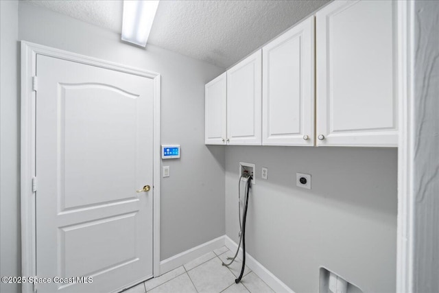 clothes washing area with hookup for a washing machine, a textured ceiling, electric dryer hookup, cabinet space, and light tile patterned floors