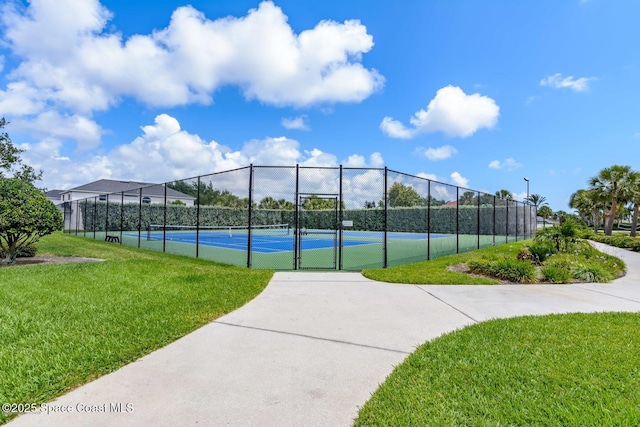 view of tennis court featuring fence and a yard