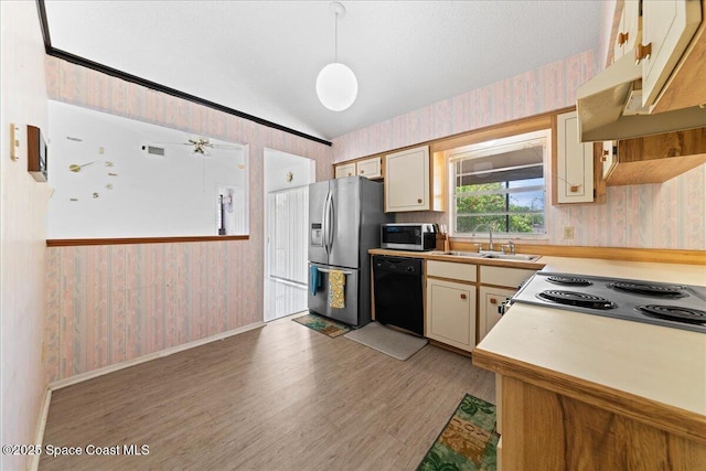 kitchen with wallpapered walls, a sink, lofted ceiling, and stainless steel appliances