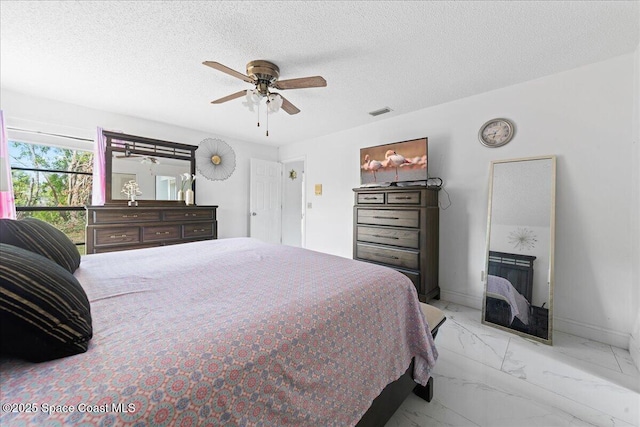 bedroom with visible vents, marble finish floor, baseboards, a textured ceiling, and a ceiling fan