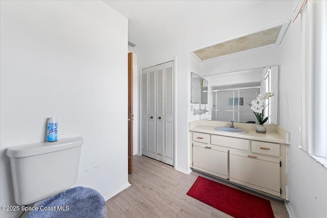 full bathroom featuring vanity, toilet, baseboards, wood finished floors, and a stall shower