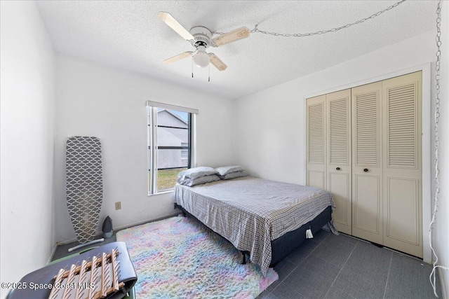 bedroom featuring dark tile patterned flooring, a textured ceiling, ceiling fan, and a closet