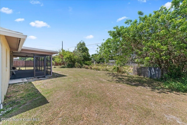 view of yard featuring fence and a sunroom