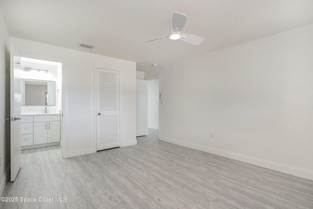 unfurnished bedroom featuring baseboards, visible vents, ensuite bathroom, and light wood-type flooring