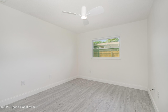 spare room featuring light wood-style floors, baseboards, and ceiling fan