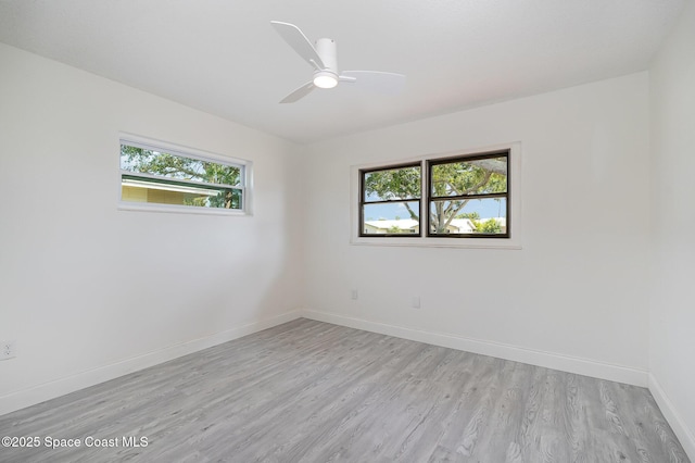 spare room with a healthy amount of sunlight, baseboards, ceiling fan, and light wood-type flooring