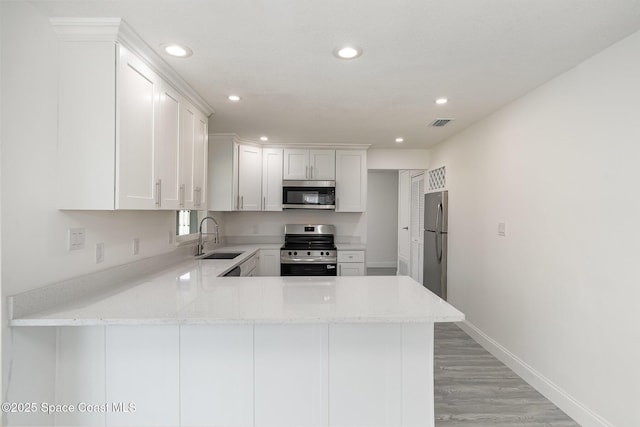 kitchen featuring recessed lighting, appliances with stainless steel finishes, a sink, and a peninsula