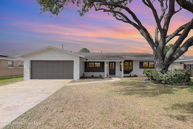 ranch-style home featuring a lawn, a garage, brick siding, and concrete driveway