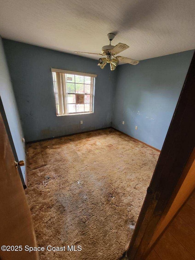 carpeted spare room featuring a textured ceiling and ceiling fan