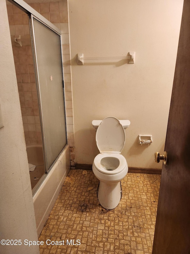 full bath with toilet, baseboards, and combined bath / shower with glass door