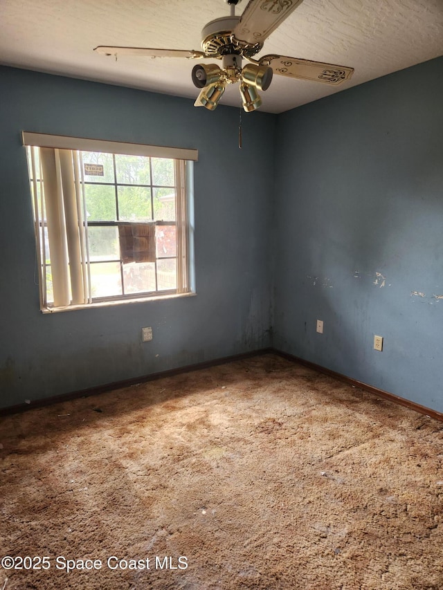 carpeted empty room with ceiling fan and baseboards