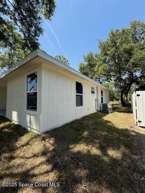 view of side of property featuring a lawn and cooling unit