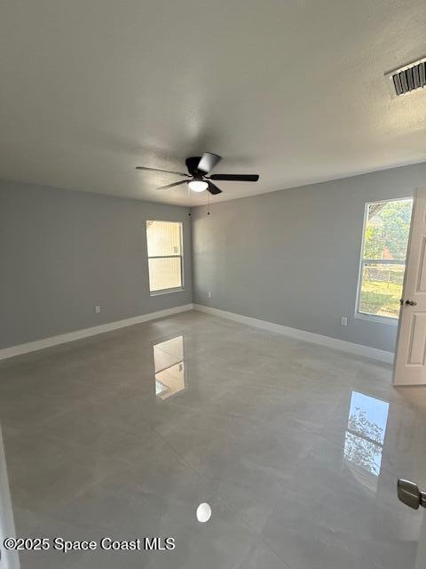 spare room with baseboards, ceiling fan, and visible vents