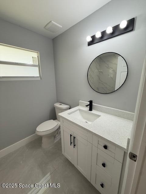 half bathroom featuring toilet, baseboards, marble finish floor, and vanity