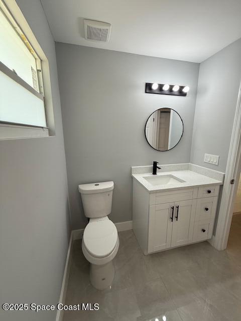 half bathroom featuring vanity, baseboards, toilet, and visible vents