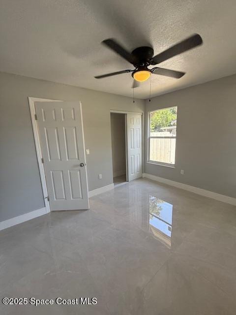 empty room featuring a ceiling fan, baseboards, and a textured ceiling