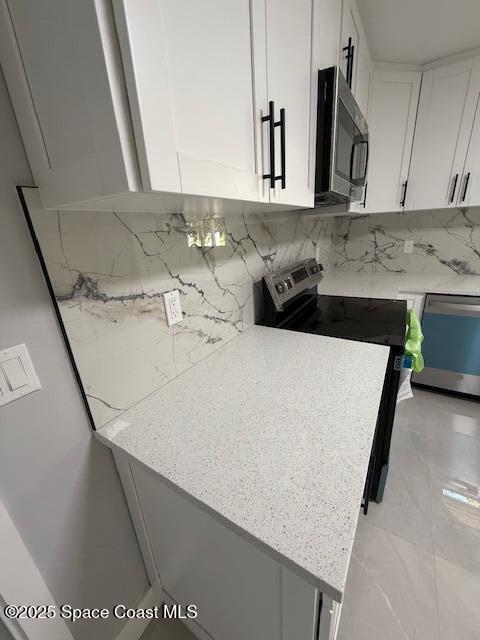 kitchen featuring marble finish floor, white cabinetry, tasteful backsplash, and stainless steel appliances