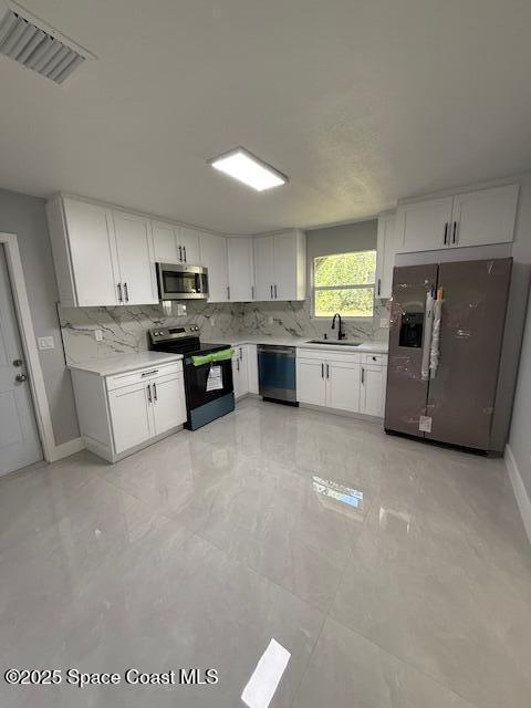 kitchen with visible vents, a sink, backsplash, and stainless steel appliances