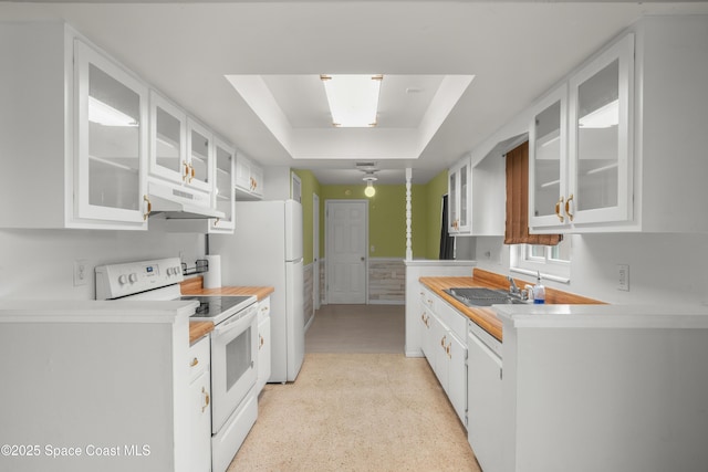 621 Plymouth St, Melbourne, FL 32935 - kitchen with white cabinets, a sink, white appliances, light countertops, and a tray ceiling