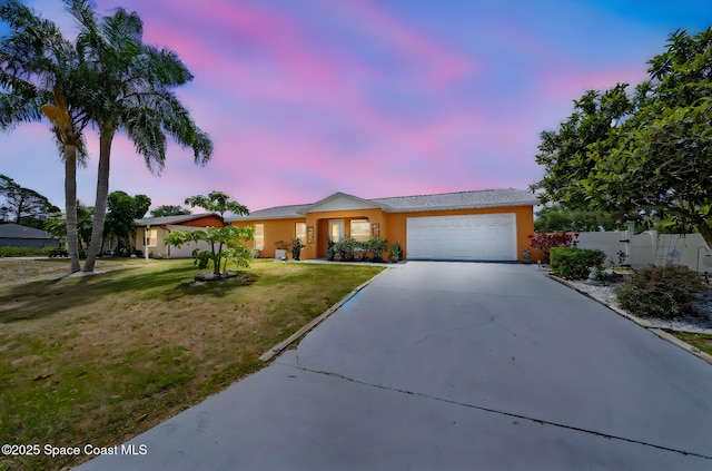 ranch-style home with a garage, fence, stucco siding, concrete driveway, and a lawn