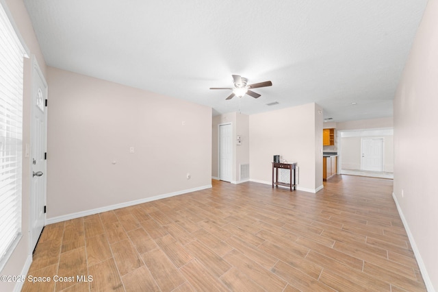 unfurnished living room featuring visible vents, a ceiling fan, light wood finished floors, and baseboards
