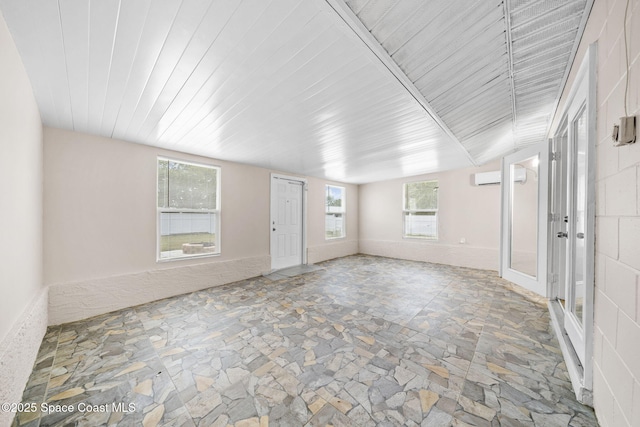unfurnished room featuring stone flooring and a wall mounted air conditioner