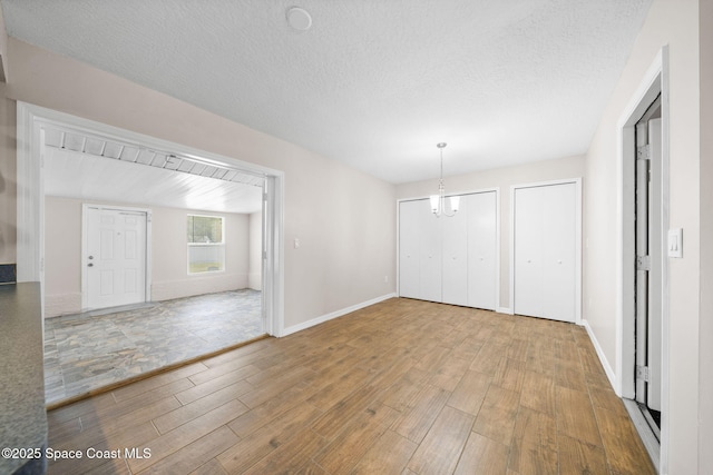 unfurnished dining area with baseboards, a textured ceiling, and wood finished floors