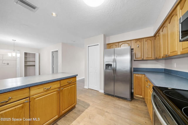 kitchen with brown cabinets, dark countertops, appliances with stainless steel finishes, light wood-type flooring, and visible vents