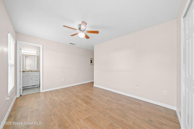 unfurnished bedroom featuring light wood-style floors, baseboards, ensuite bathroom, and visible vents