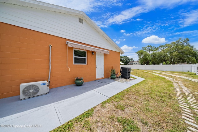 view of home's exterior featuring fence, ac unit, concrete block siding, central air condition unit, and a yard