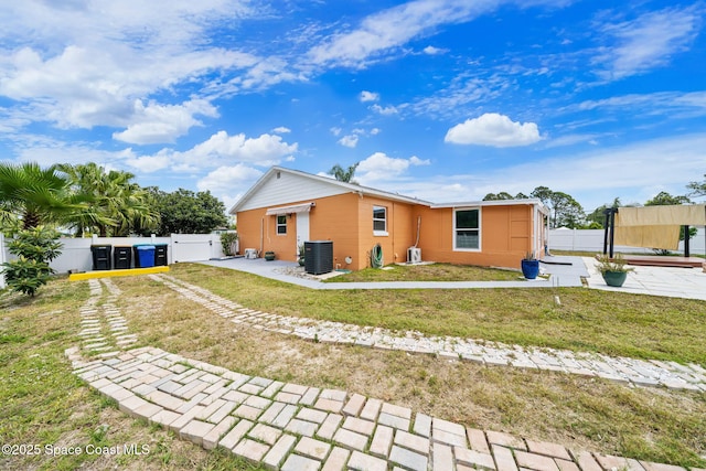 exterior space with a lawn, a gate, fence, and cooling unit