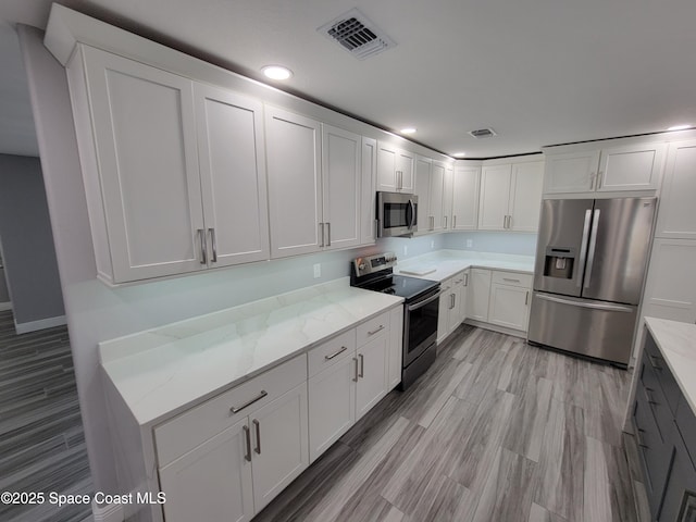 2175 Dumas St, Merritt Island, FL 32952 - kitchen with stainless steel appliances, light stone counters, white cabinets, recessed lighting, and light wood-style flooring