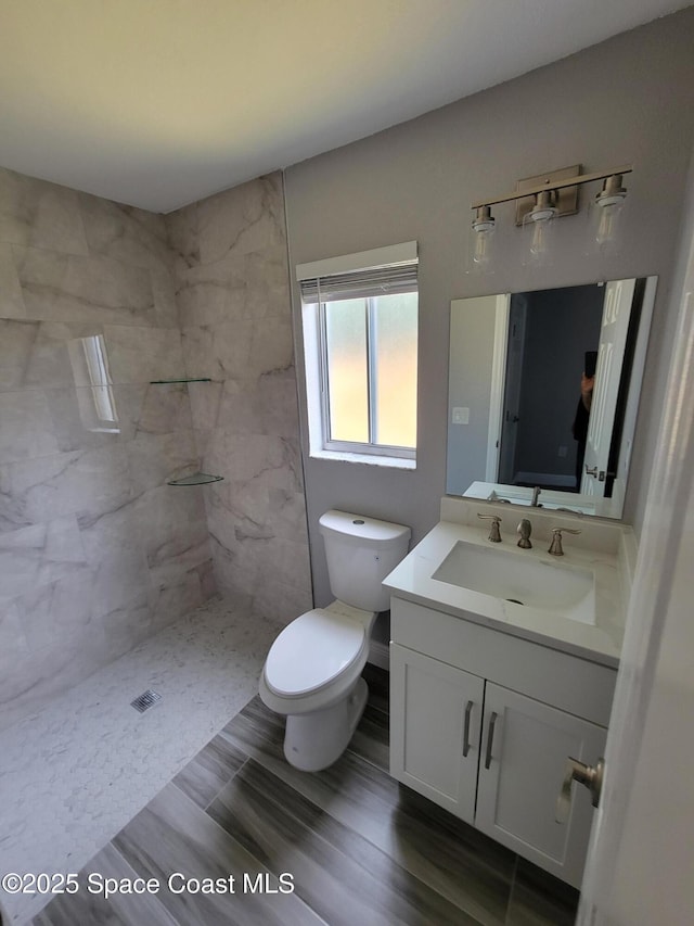 2175 Dumas St, Merritt Island, FL 32952 - bathroom featuring vanity, toilet, a tile shower, and wood finished floors