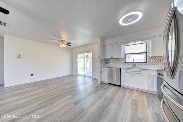 kitchen featuring visible vents, a sink, a ceiling fan, light wood-style flooring, and stainless steel appliances