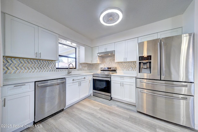 kitchen featuring light countertops, stainless steel appliances, white cabinetry, and under cabinet range hood