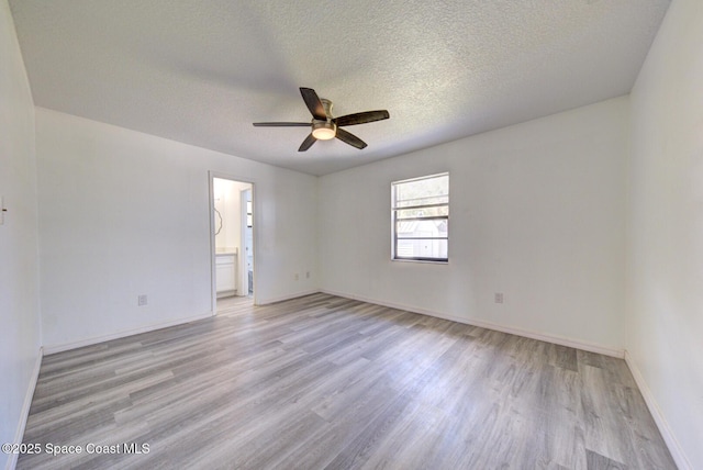 spare room featuring a ceiling fan, a textured ceiling, baseboards, and light wood finished floors