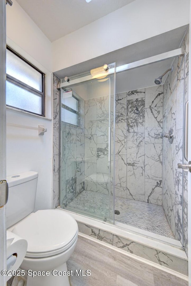 full bathroom featuring a marble finish shower, wood finished floors, and toilet