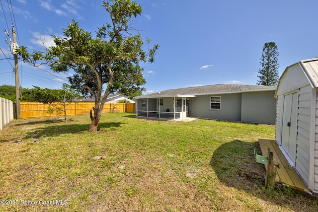 view of yard with an outbuilding, a fenced backyard, and a sunroom