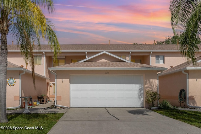 view of property featuring a garage, stucco siding, and concrete driveway