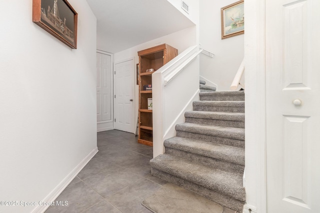 stairway featuring tile patterned floors, baseboards, and visible vents