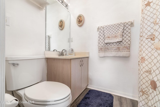full bathroom with toilet, baseboards, wood finished floors, and vanity