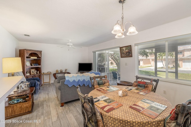 dining space with ceiling fan with notable chandelier, light wood-style flooring, and visible vents