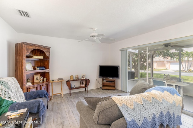 living area with ceiling fan, visible vents, and wood finished floors
